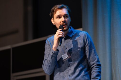 Kuvassa mieshenkilö puhuu mikrofoniin.