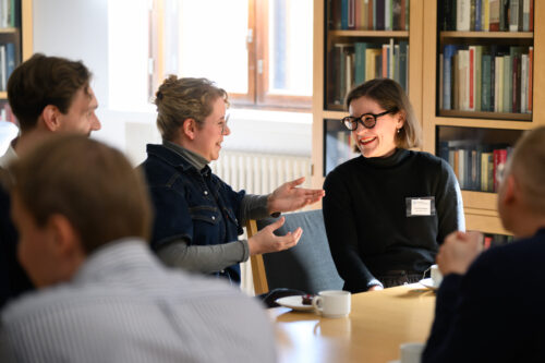 In the picture, five people are sitting around a table engaged in a lively discussion.
