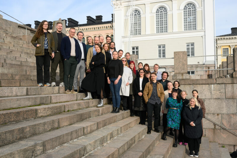 A group of people standing on a staircase. Many of them are smiling.