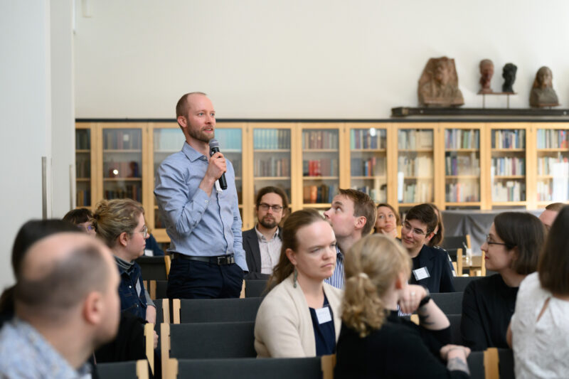 Samuli Autti seisoo ja puhuu mikrofoniin kokouksessa.