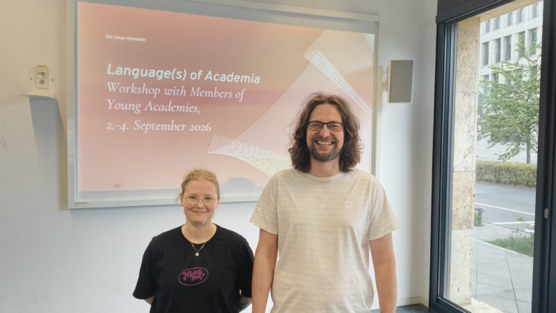 Minttu Smith ja Sampsa Holopainen seisovat hymyilevinä kyltin edessä, jossa lukee language(s) of academia